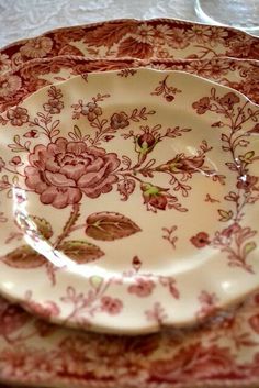 two plates are stacked on top of each other, one is red and the other has pink flowers