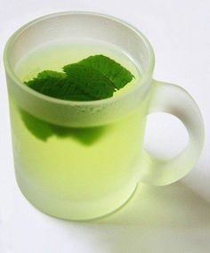 a glass cup filled with green tea on top of a white table