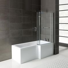 a bathroom with a bathtub, shower and tiled walls in grey tones on the floor