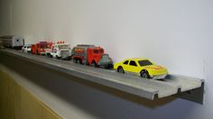 toy cars and trucks are lined up on the shelf in front of the wall,