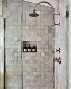 a walk in shower sitting next to a white sink and toiletries on top of a tiled wall