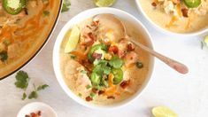 two bowls filled with soup and garnished with cilantro, jalapenos, and limes