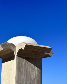 the top of a wooden structure with a large white ball on it's end