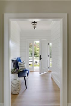 an open door leading to a hallway with white walls and wood flooring on both sides