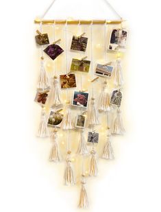 a white wall hanging with pictures and lights on the side, along with tassels