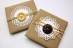 two brown gift bags with lace and buttons on them, one has a gold button