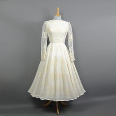 a white dress on a mannequin with long sleeves and a bow at the waist