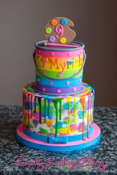 a three tiered cake decorated with colorful icing