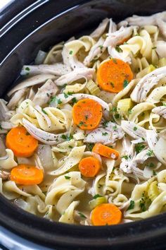 a crock pot filled with chicken noodle soup, carrots and parsley