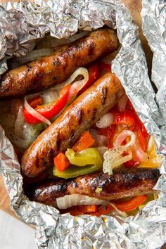 sausages, peppers and onions in foil on a wooden table