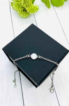 a book with a chain around it and a white pearl on the front, sitting next to a green plant