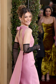 a woman in a pink dress and black gloves on the red carpet at an event