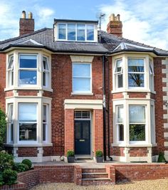 a large brick house with many windows and steps leading up to the front door area