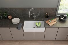 a white sink sitting on top of a counter next to a wooden cutting board and bowl