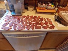 bacon is laid out on a cutting board in front of an oven and counter top