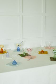 a white table topped with lots of different colored dishes and glasses on top of it