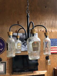 three liquor bottles hanging from a chandelier in front of an american flag on the wall