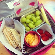 the lunch box is filled with different types of snacks and fruit, including crackers