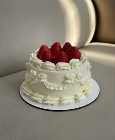 a white cake topped with strawberries on top of a table next to a plate