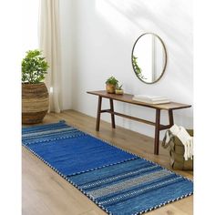 a room with a table, mirror and blue rug on the floor in front of it