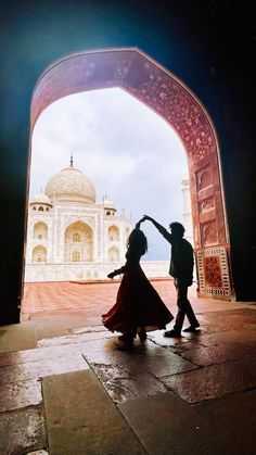 two people dancing in front of an archway