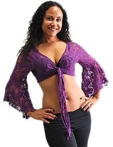 a woman in a purple top and black pants posing for the camera with her hands on her hips