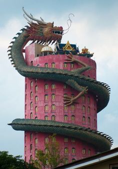 a tall pink building with a dragon statue on top