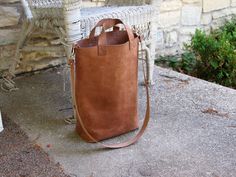 a brown leather bag sitting on top of a stone bench