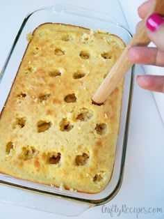 a person holding a wooden spoon over a casserole dish