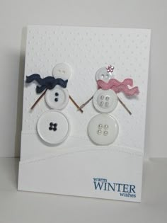 two snowmen made out of buttons sitting on top of a white card with the words winter written in it