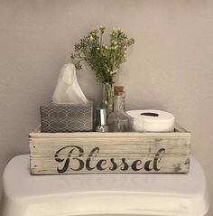 a toilet with a wooden sign that says, blessing bathroom decoration above it is a tissue dispenser and flowers