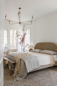 a bedroom with a bed, two chairs and a chandelier hanging from the ceiling