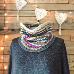 a knitted cowgirl neck scarf hanging on a string with lights in the background