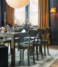 a dining room table and chairs with candles on the windowsills in front of them