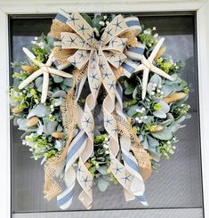 a wreath with starfishs and greenery hangs on the front door