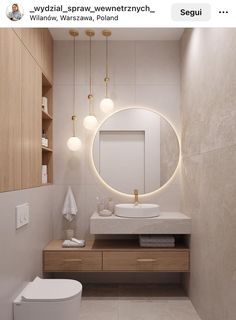 a white toilet sitting next to a bathroom sink under a round mirror on a wall