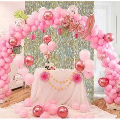 a table topped with pink balloons next to a wall