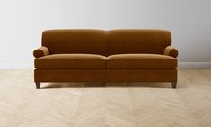 a brown couch sitting on top of a hard wood floor next to a white wall