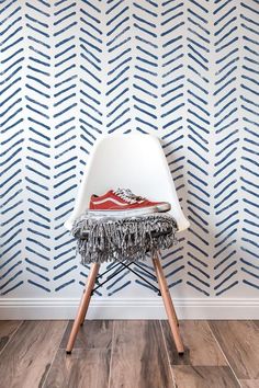 a white chair sitting in front of a wall with blue and white designs on it