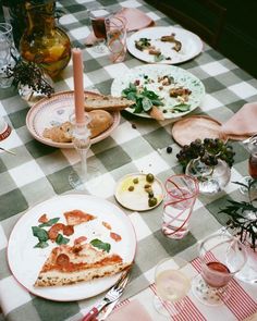 a table topped with plates and pizza on top of a checkerboard table cloth