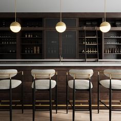 a bar with four stools and several bottles on the shelves behind it, all lined up