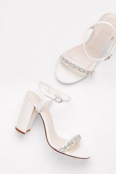 two women's white shoes with jewel embellishments on the toes and heel