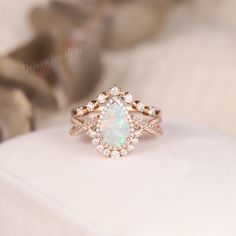 an opal and diamond ring sits on a white cushion