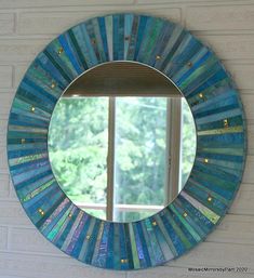 a round blue mirror hanging on the side of a white wall next to a window