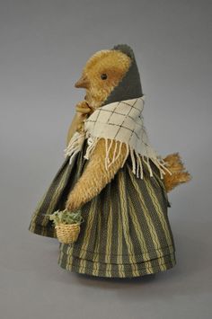 a teddy bear dressed in a dress with a scarf around it's neck and holding a basket