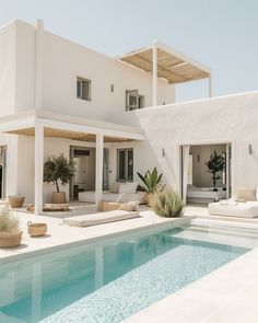 a large white house with a pool and lounge chairs around the outside swimming pool in front of it