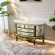 a white and green dresser sitting on top of a wooden floor next to a plant