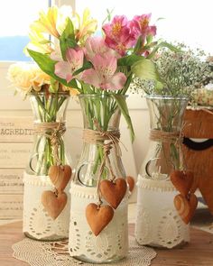 three vases with flowers in them on a table