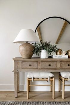 a wooden table topped with two lamps next to a mirror