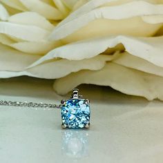 "-Approximate total carat weight: 1.70ctw diamond equivalent -Center Stone Size: approx. 1.70ct diamond equivalent -Center Stone Shape: cushion cut 7x7mm -Gem Type: lab created Aquamarine -Stone Clarity: VS2 -Stone Color: lively medium light blue eye-clean -Moh's Scale: 8.5 hardness -Metal Type and Purity: 14k white gold -Setting: 4 prong basket head -Chain: 18\" delicate 14k gold chain (heavier chain is available contact us for pricing) -Country of Manufacturing: USA (Michigan) For customizatio Fine Jewelry Blue Necklace For Anniversary, Blue Necklaces For Anniversary In Fine Jewelry Style, Blue Fine Jewelry Necklace For Anniversary, Blue Gemstone Birthstone Necklace For Anniversary, Blue Birthstone Necklace In Fine Jewelry Style, Light Blue Jewelry With Prong Setting For A Gift, Blue Necklaces With Prong Setting For Gifts, Blue Diamond Cut Round Cut Necklaces, Light Blue Birthstone Necklace For Anniversary